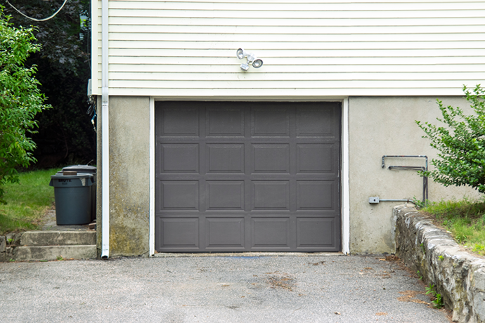 Grey garage door on residential property with concrete driveway.