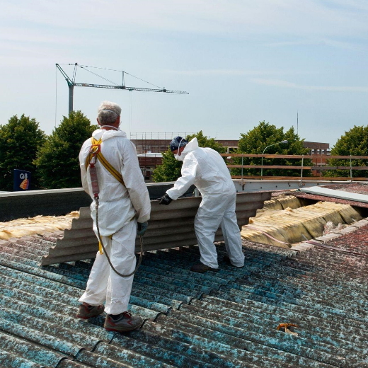 Two men removing asbestos-containing materials from a roof. 