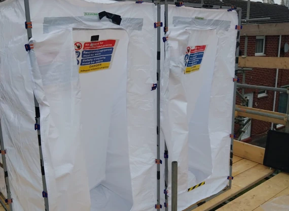 Asbestos decontamination units set up outdoors on scaffolding. 