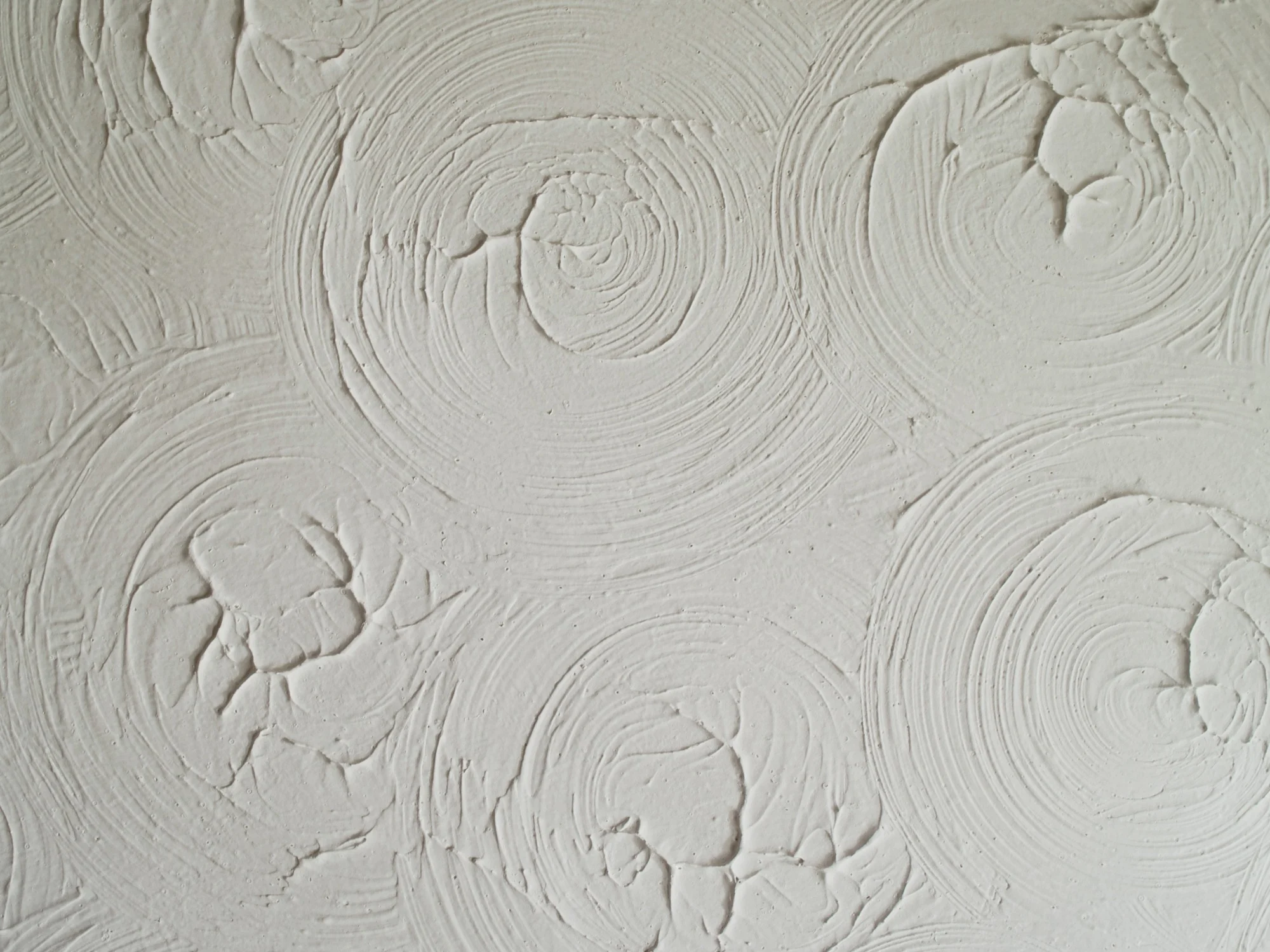 Close-up of a white textured ceiling with a swirling ‘Artex’ pattern.