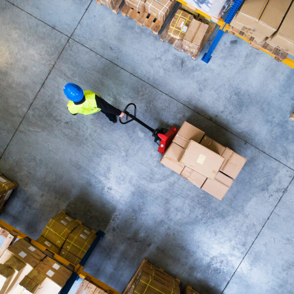 Male worker pulling a trolley through warehouse facility