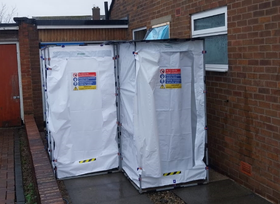Two asbestos removal tents set up outside of a domestic property.