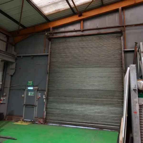 An industrial warehouse with grey walls and a corrugated roof.