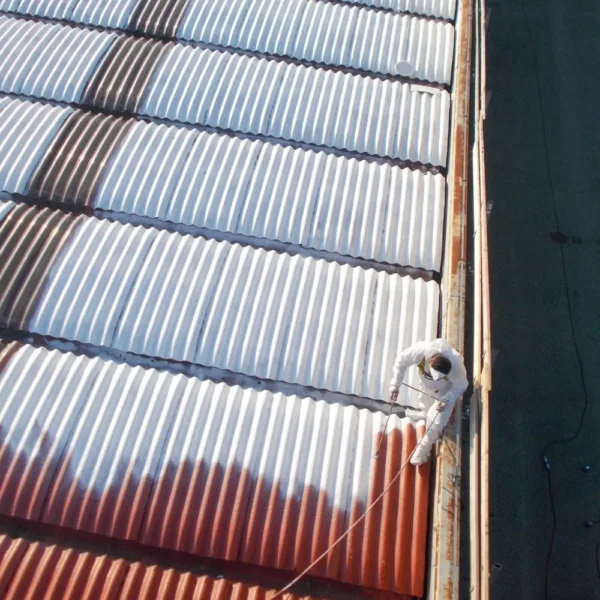 A person spraying a metal industrial roof.